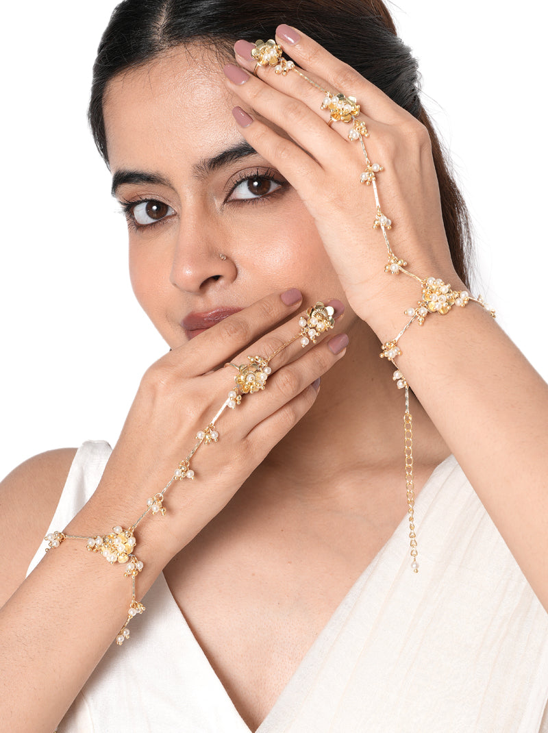 Adhika Delicate Pearl Hathphool pair handcrafted with floral faux pearl motifs, intricate glass bead detailing, elegant hand chains, and a Gold Tone Finish, perfect for Haldi, Mehndi, weddings, receptions, engagement ceremonies, destination weddings, and sophisticated bridal hand styling.