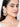 Charvi Floral Shell Earrings featuring cowrie shell floral motifs, faux pearl detailing, ear chain support and a gold tone finish for bridal and festive wear.