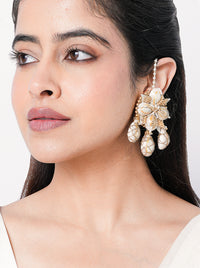 Charvi Floral Shell Earrings featuring cowrie shell floral motifs, faux pearl detailing, ear chain support and a gold tone finish for bridal and festive wear.