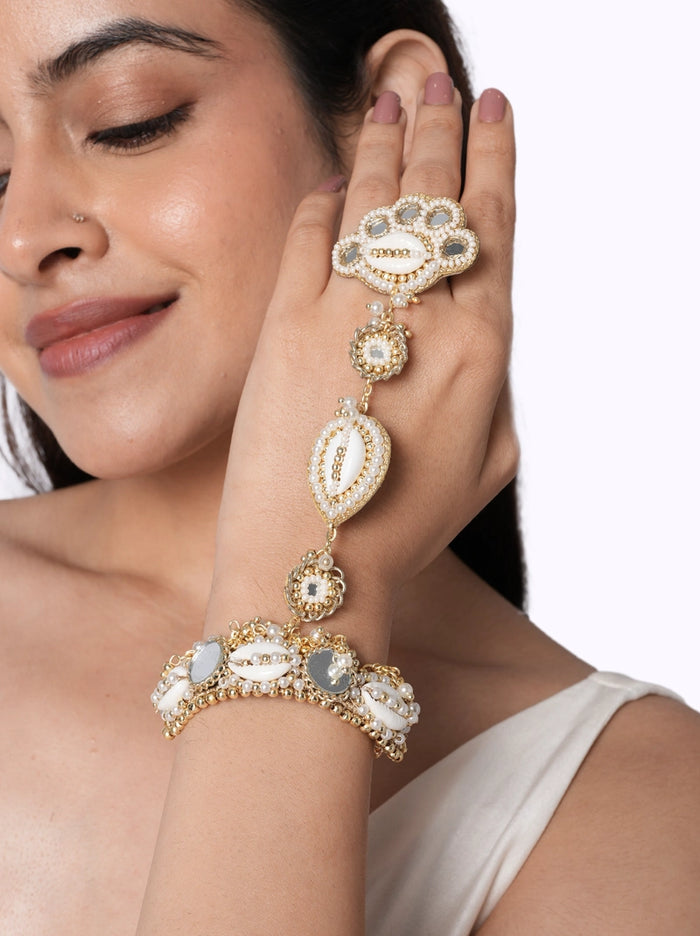 Dwani Shell Mirror Hathphool handcrafted with natural shell accents, mirror details, faux pearls, glass bead embroidery, and a Gold Tone Finish, perfect for haldi ceremonies, destination weddings, festive occasions, and contemporary bridal styling.