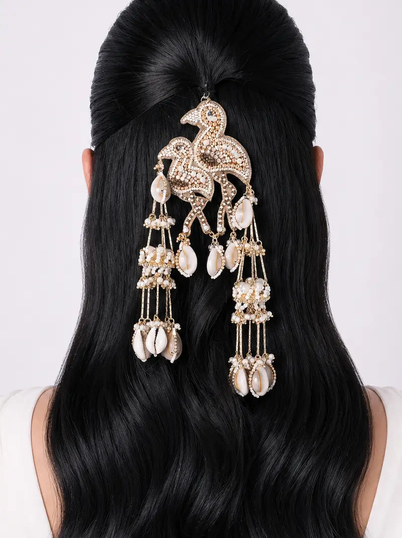 Falguni Flamingo Hair Accessory featuring sparkling crystal stones, cowrie shells, faux pearls, cascading tassels and a gold tone finish, ideal for bridal hairstyles, destination weddings and festive celebrations.