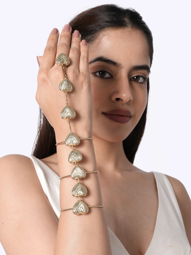 Hansi Handcrafted Heart Hathphool crafted from textured brass metal heart motifs with a Gold Tone Finish, featuring an adjustable ring and open cuff design, perfect for weddings, festive occasions, cocktail parties, and contemporary ethnic styling.