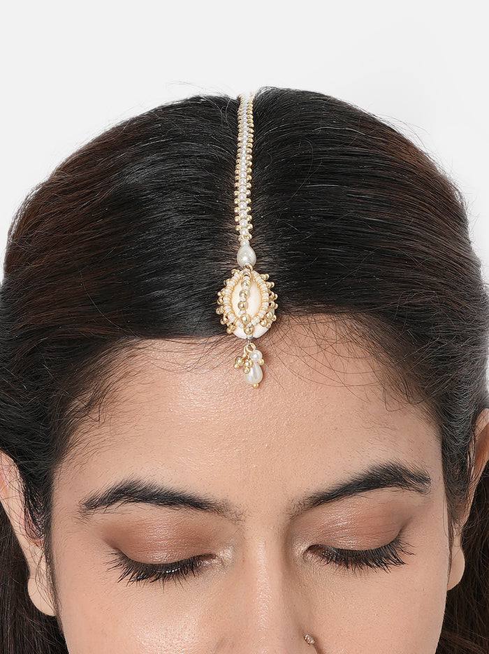 Rashmi Shell Festive Maangtika handcrafted with a natural cowrie shell centerpiece, faux pearls, glass bead embroidery, and a Gold Tone Finish, perfect for Haldi, Mehndi, intimate weddings, festive celebrations, poojas, and elegant bridal styling.