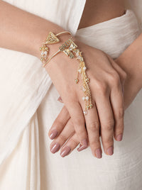 Rutvi Bride Charm Bracelet handcrafted with a circular mirror centerpiece, faux pearl border, intricate glass bead detailing, brass metal, and a Gold Tone Finish, perfect for weddings, Haldi, Mehndi, festive celebrations, parties, and elegant ethnic styling.