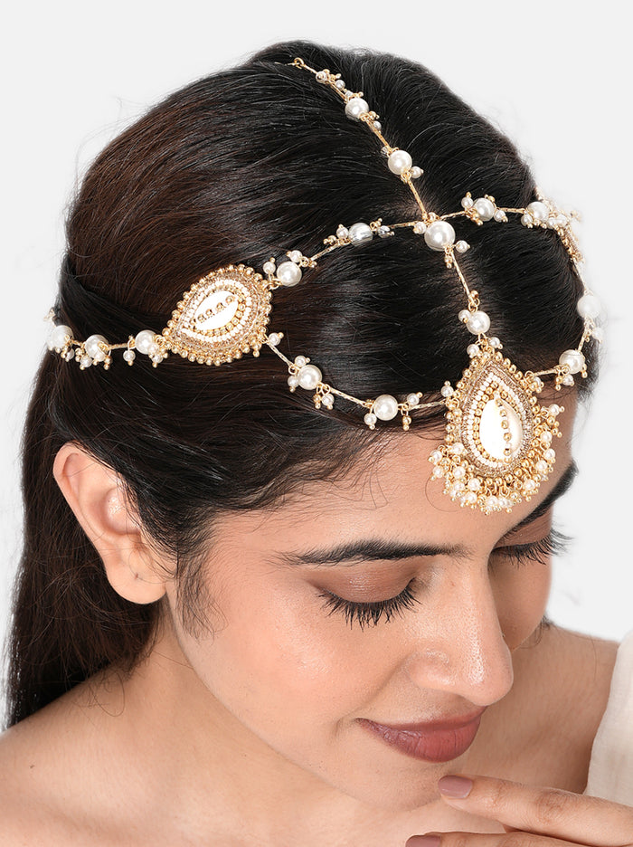 Saloni Shell Designer Maathapatti handcrafted with natural cowrie shell motifs, faux pearl strands, intricate glass bead detailing, and a Gold Tone Finish, perfect for bridal entries, Haldi, Mehndi, Sangeet, weddings, receptions, destination weddings, and elegant bridal hairstyles.