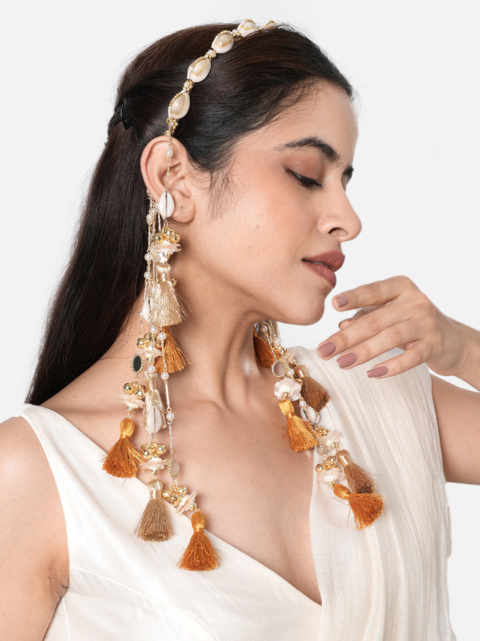 Siya Shell Tassel Hairband handcrafted with natural cowrie shells, faux pearls, glass bead detailing, cascading thread tassels, and a Gold Tone Finish, perfect for Haldi, Mehndi, destination weddings, festive celebrations, beach weddings, and elegant bridal hairstyles.