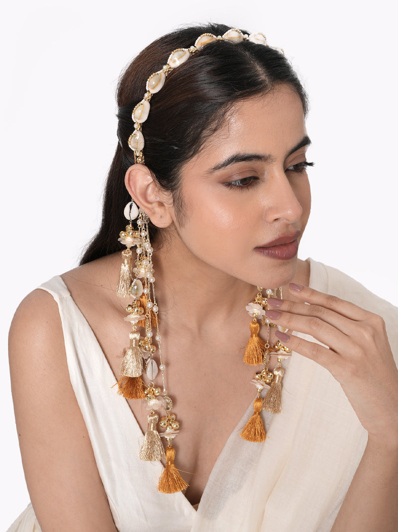 Siya Shell Tassel Hairband handcrafted with natural cowrie shells, faux pearls, glass bead detailing, cascading thread tassels, and a Gold Tone Finish, perfect for Haldi, Mehndi, destination weddings, festive celebrations, beach weddings, and elegant bridal hairstyles.