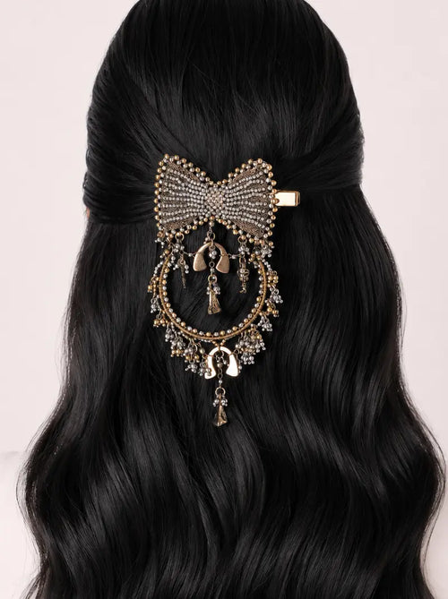 Divya Bow Hair Accessory handcrafted in antique silver and antique gold finish featuring an embellished bow design with cascading charms for bridal, festive and party hairstyles.