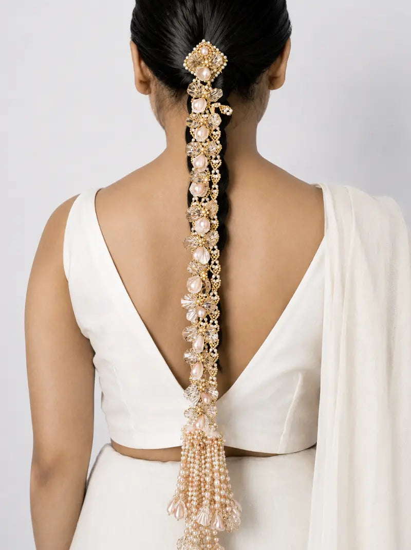 Jiva Haldi Pearl Braid handcrafted with blush floral motifs, faux pearls, crystal accents and cascading pearl tassels in a Gold Tone Finish for elegant Haldi and bridal hairstyles.